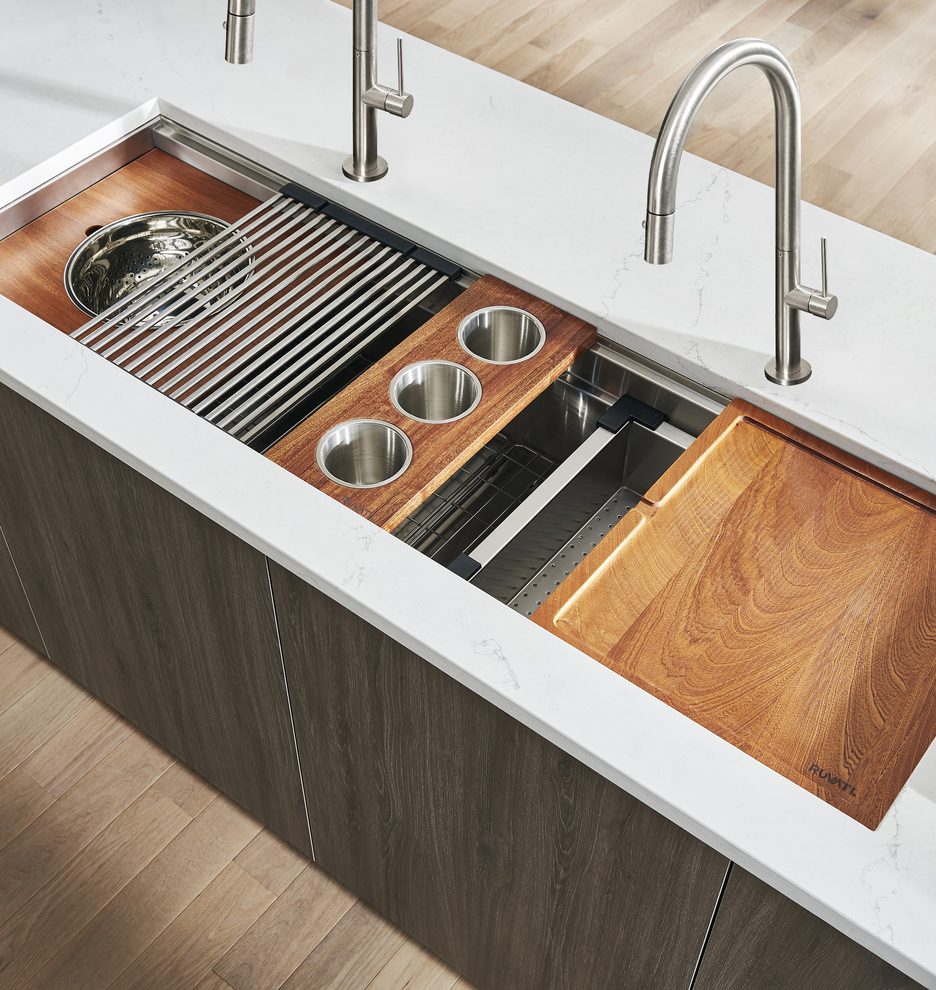 Oversize kitchen workstation sink with cutting board drying rack mixing bowl colander on marble countertop